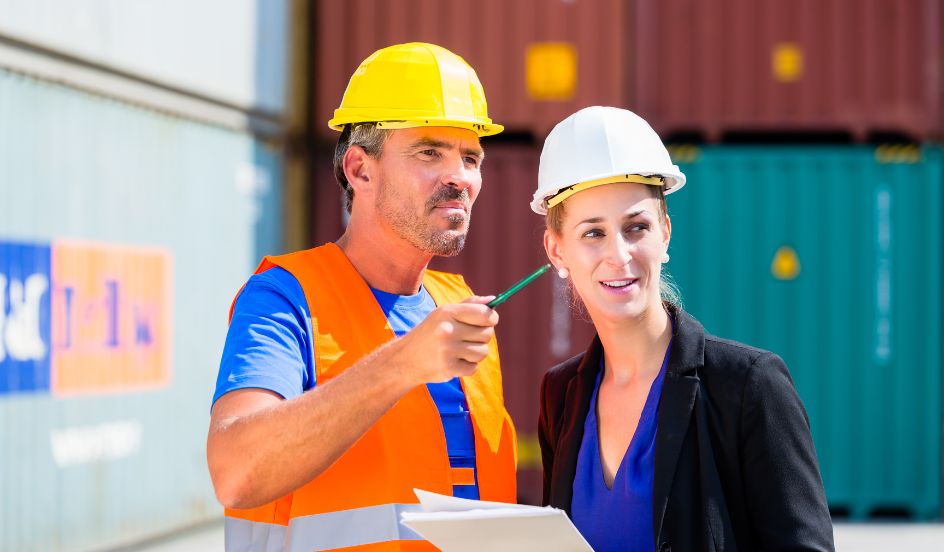 male and female in shipping yard discussing logistics