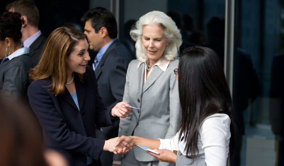 group of professional women shaking hands and exchanging business cards networking