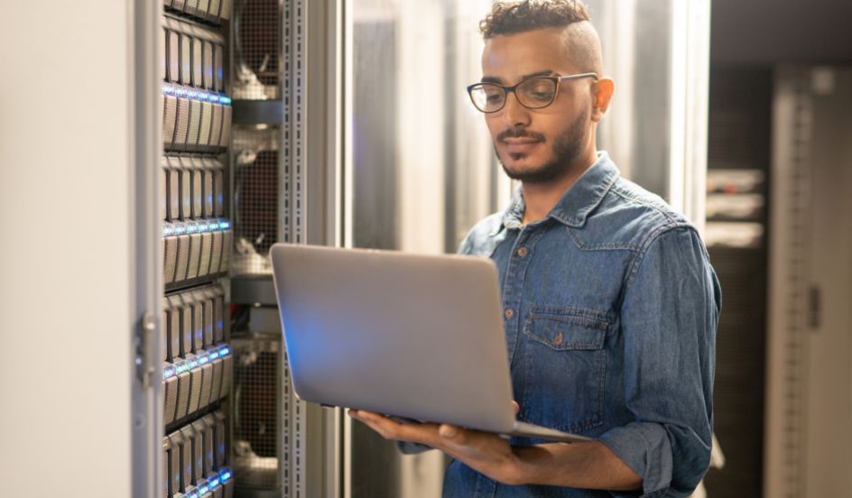 IT specialist working in sever room with laptop