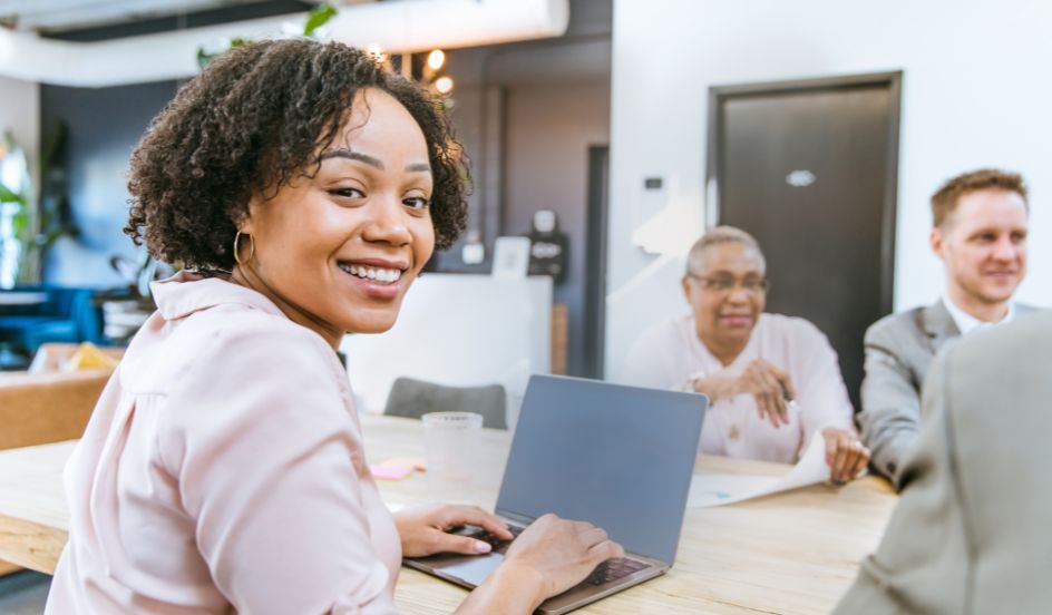 woman smiling while on laptop in meeting as in apprenticeship 