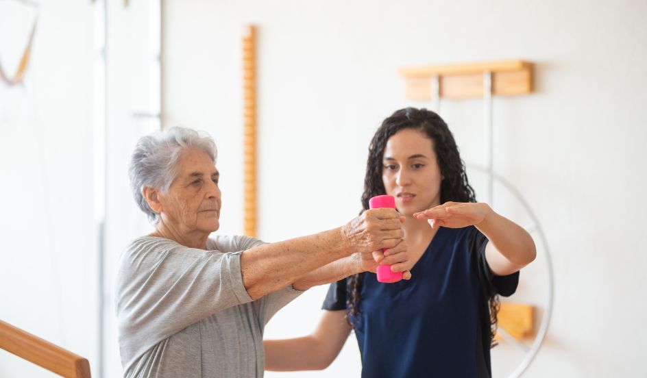 occupational therapist assistant helping patient with arm weights