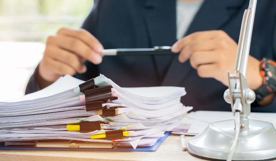 pile of legal papers clipped together with person holding pen in background