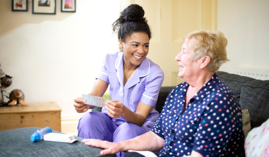 female psw sitting with senior female helping with medication