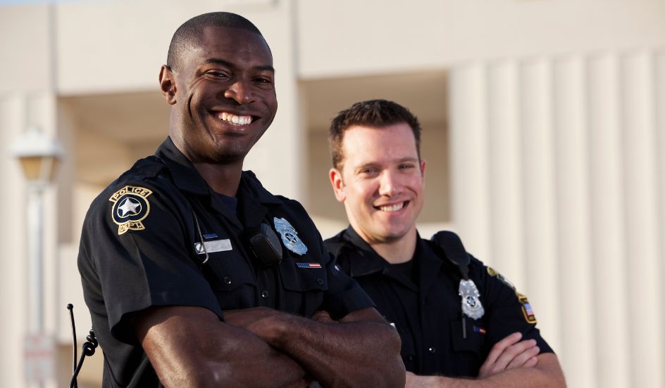 two male police officers standing with arms crossed smiling