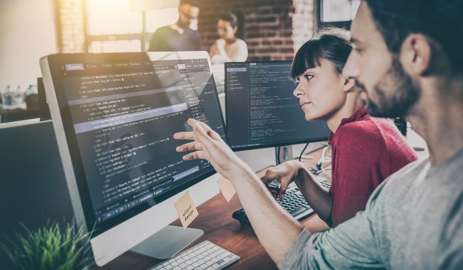 male and female looking at coding on a computer screen