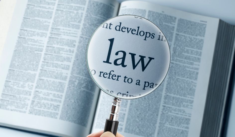 open law book with a magnifying glass focusing on the word law