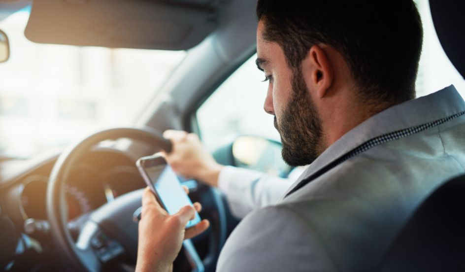 man holding phone while driving