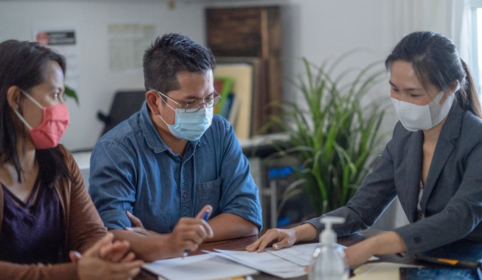 male and female sitting at desk looking over papers with professional female