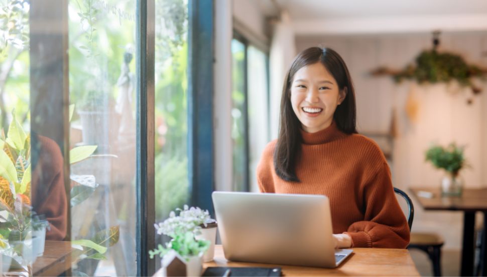 woman smiling sitting at a desk in front of a laptop