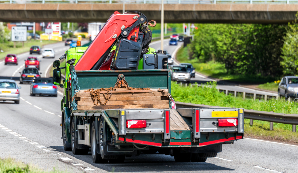 truck driving on highway carrying machinery