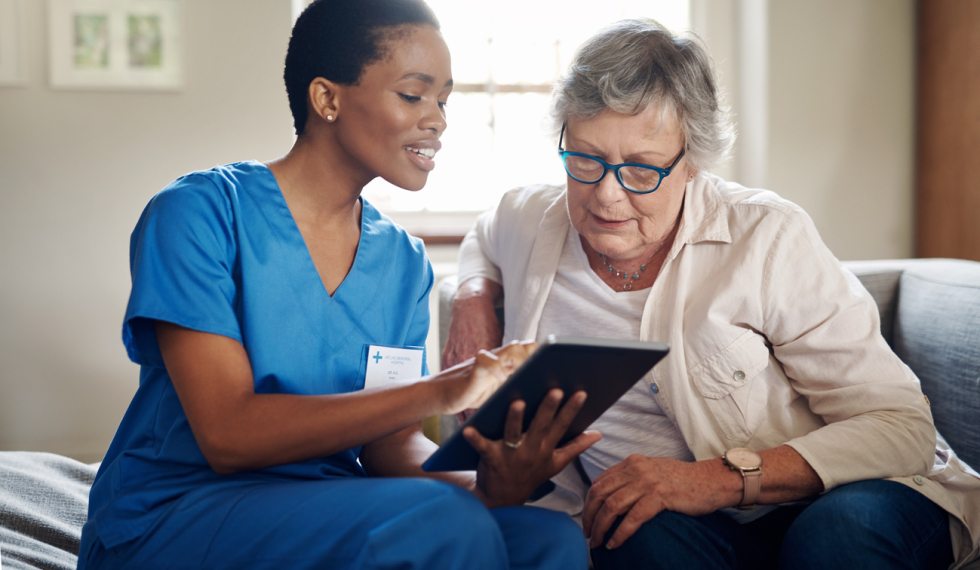 female psw working with elderly patient showing her information on a tablet