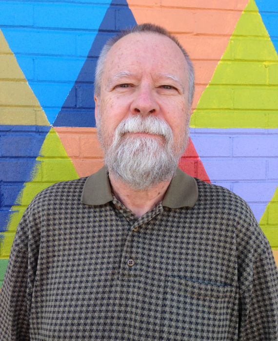 male grad from triOS standing in front of wall with triangles