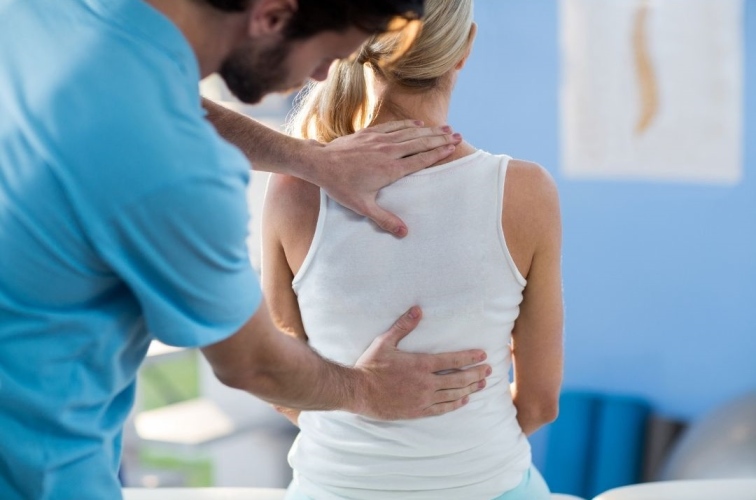 Physiotherapy assistant examines a patient's back